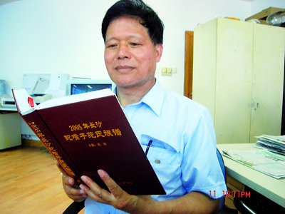 图为范羽正在阅读自己编纂的《长沙蛇嘴子范氏族谱》。李姝阳摄